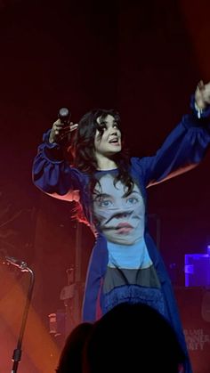 a man with long hair on stage holding a microphone