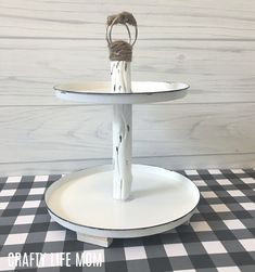 two tiered serving tray with rope wrapped around the top on a black and white checkered tablecloth