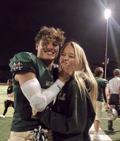 a man and woman hugging each other at a football game