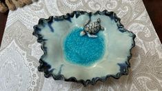 a blue bowl with a turtle on it sitting on top of a white tablecloth