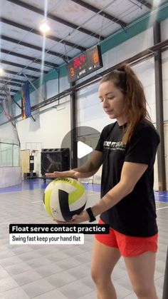 a woman in black shirt holding a yellow and white ball inside of a gym area