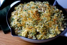 a casserole dish with broccoli and cheese in it on a wooden table