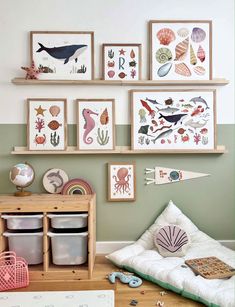 there are many pictures hanging on the wall in this child's room, including sea animals and seashells