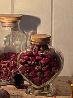 two glass jars filled with flowers sitting on top of a wooden table next to other items