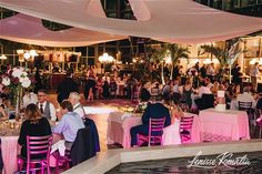 a large group of people sitting at tables in a room with pink and white decor