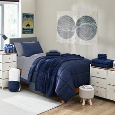 a bed room with a neatly made bed and dressers next to a large window