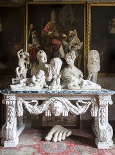 a table with statues on it in front of paintings