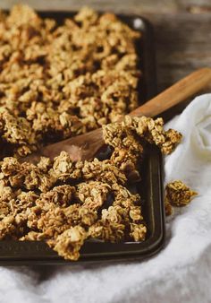 a pan filled with granola next to a wooden spoon