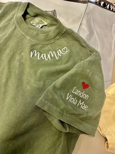 ✨UNISEX COMFORT COLORS C1717 SHORT SLEEVE TEE✨ Custom Embroidered Mama Shirt ➡️Features: * Unisex sizing. * 100% ring-spun cotton * Relaxed fit * Sewn-in twill label * Medium fabric (6.1 oz/yd² (206.8 g/m Want the trendy oversized dress look? Order 2 sizes larger than your usual size. 📏👚Easy measuring tip: Take your favorite shirt, lay it on a flat surface and measure the width (armpit to armpit) and length (top to bottom) and compare with your favorite shirt. ✨For sizing, check out the chart in the product photos. ❤️Custom Request? Please send me a message before you order : ✨Returns We do not take returns or exchanges due to being custom. If you have any issues please send me a message. ✨Production and Shipping Processing is 1 day. First Class Shipping is 2-5 business days (after proce Green Embroidered Text Short Sleeve T-shirt, Casual T-shirt With Embroidered Text For Mother's Day, Basic Relaxed Fit Top With Custom Embroidery, Basic Cotton Tops With Custom Embroidery And Relaxed Fit, Mother's Day Cotton T-shirt With Embroidered Graphics, Cotton Tops With Letter Embroidery For Mother's Day, Basic Green Shirt With Letter Print, Green Basic Shirt With Letter Print, Embroidered Green Cotton Shirt