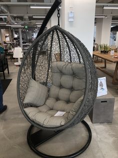 a hanging egg chair with cushions on display in an office building or showroom,