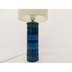 a blue lamp with a white shade on it's base and a light plugged in