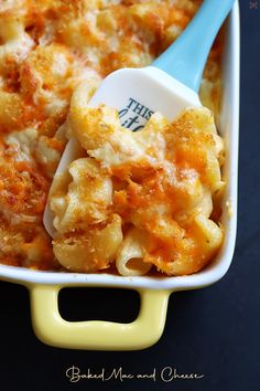 a casserole dish filled with macaroni and cheese, topped with a blue spoon