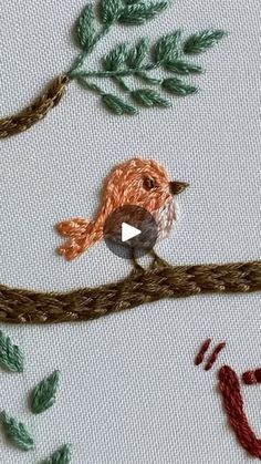 an embroidered bird sitting on top of a tree branch with leaves and branches around it