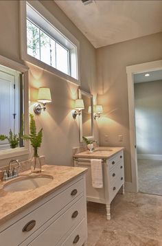 a bathroom with double sinks and two lamps on either side of the sink, in front of an open door