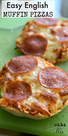 two small pizzas sitting on top of a green cutting board