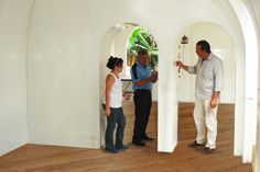 three people standing in a room with white walls