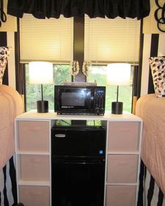 a microwave on top of a dresser in a room with two beds and a window