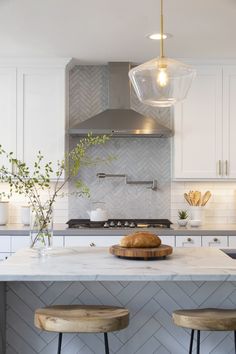 a kitchen island with two stools and a marble counter top in front of it