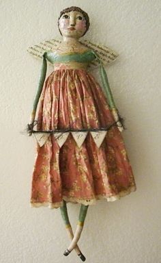 a doll is hanging on the wall next to a white wall with a red and green dress