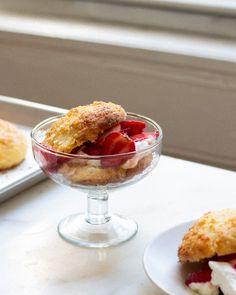 two small desserts are sitting on the table next to each other, one is filled with ice cream and strawberry shortcakes