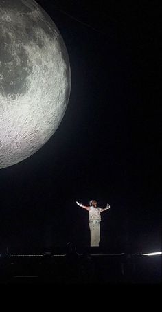 a man standing on top of a stage next to a giant moon