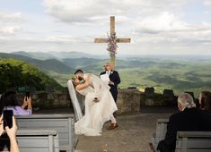 a bride and groom walking up the aisle to their wedding ceremony with mountains in the background