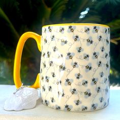 a yellow and white coffee mug sitting on top of a table next to a cookie