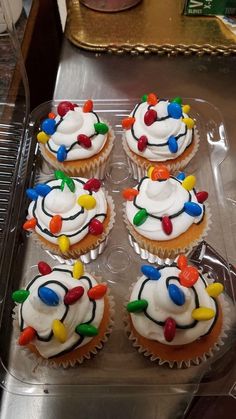 cupcakes with white frosting and colorful lights on them in a plastic container