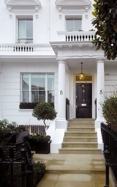 a white house with steps leading up to the front door and black railings on either side