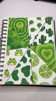 an open spiral notebook with green and white designs on it, sitting on top of a table