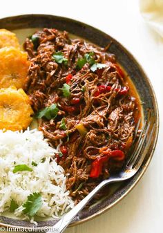 a plate filled with rice, meat and other food on top of a white table