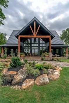 a large house with lots of windows and rocks in the front yard, surrounded by green grass