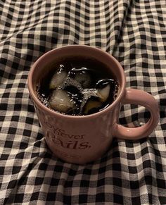 a cup filled with ice sitting on top of a checkered table cloth