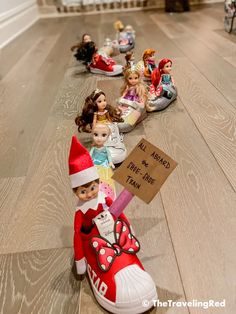 there are many dolls lined up on the floor with a sign in front of them