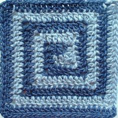 a crocheted square is shown in blue and gray colors with a white center