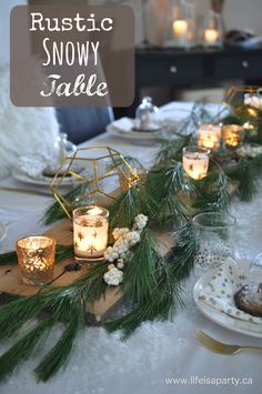 the table is set with candles, pine branches and snow globes for winter tablescape