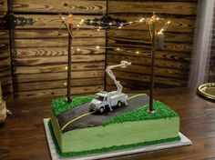 a birthday cake with a car on the road and lights strung from it's poles