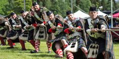 men dressed in traditional scottish clothing and holding swords