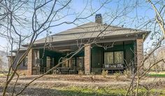 a small house sitting in the middle of a field with lots of trees around it