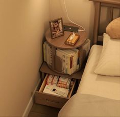 a nightstand with books on it next to a bed in a small room or bedroom