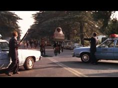 people are standing in the street with cars and motorcycles behind them, one person is holding an object over his head