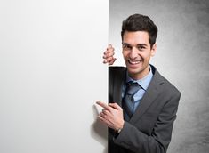 a man in a suit and tie holding onto a white board with his finger on it