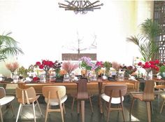 a dining room table with chairs and flowers in vases on the top one side