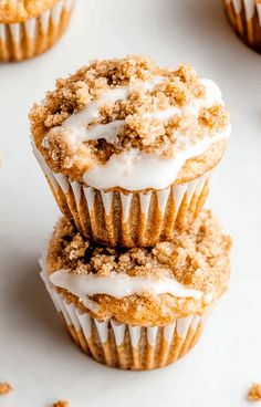 three cupcakes with white frosting and crumbs on the top one