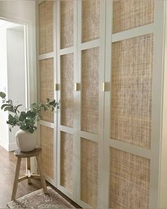 a plant is sitting on a stool in front of a large, white cabinet with glass doors