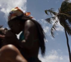 a woman standing next to a palm tree under a blue sky with clouds and sun