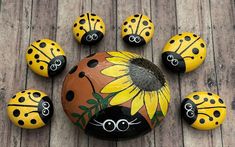 painted rocks with ladybugs and sunflowers arranged on a wooden deck for decoration