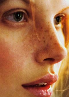 a woman with freckles on her face looking to the side, close up