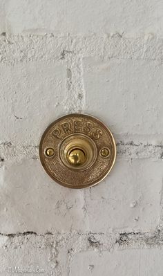 an old fashioned brass door knob on a white brick wall with the word's name engraved on it