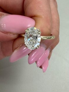 a woman's hand holding a pink manicured ring